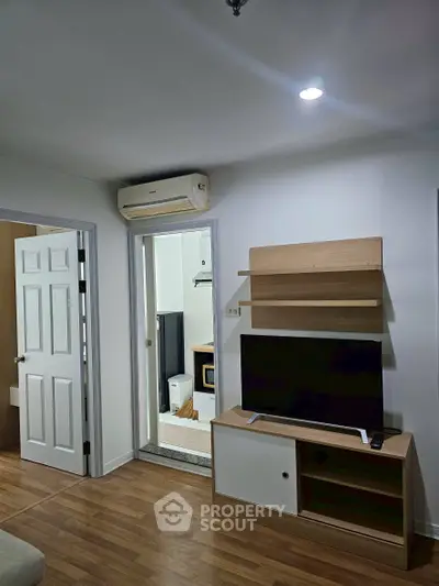 Modern living room with wooden flooring, TV unit, and air conditioning in a cozy apartment.