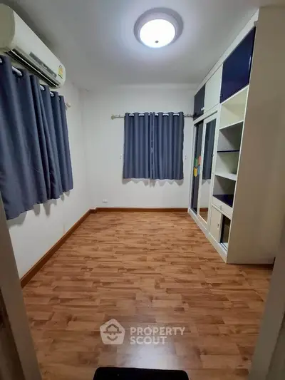 Spacious bedroom with wooden flooring and built-in wardrobe, perfect for modern living.