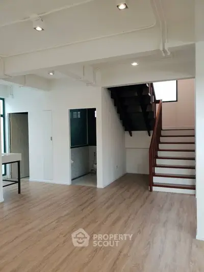 Spacious modern interior with wooden flooring and staircase, ideal for contemporary living.