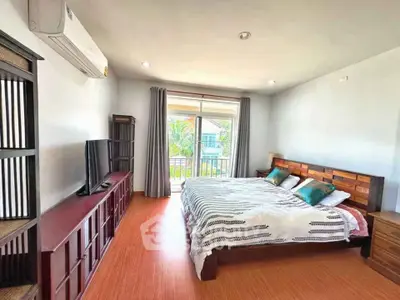 Spacious bedroom with modern decor and large window offering natural light and garden view.