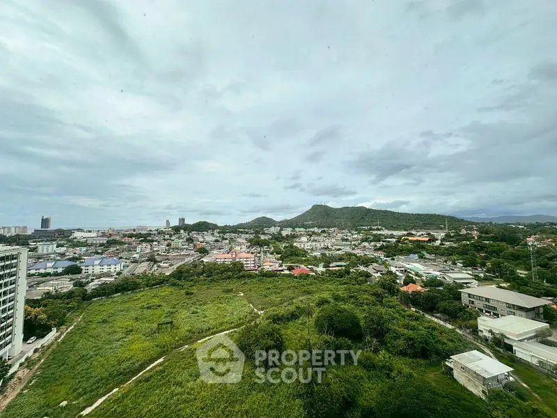 Stunning panoramic cityscape view with lush greenery and distant mountains, perfect for real estate investment.