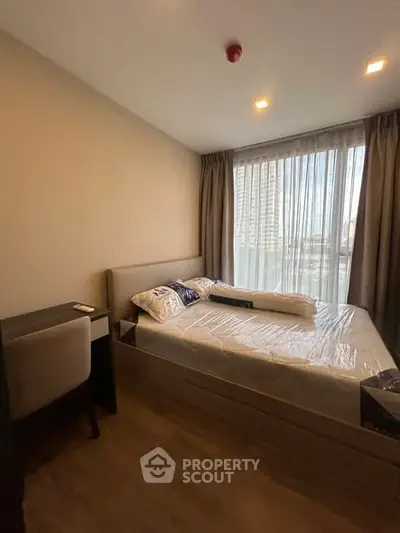 Cozy bedroom with modern furnishings and large window offering natural light.