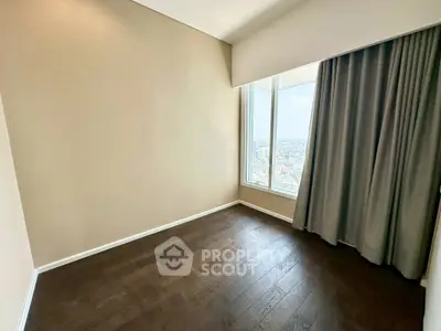 Spacious empty room with large window offering stunning city view and elegant dark wood flooring.