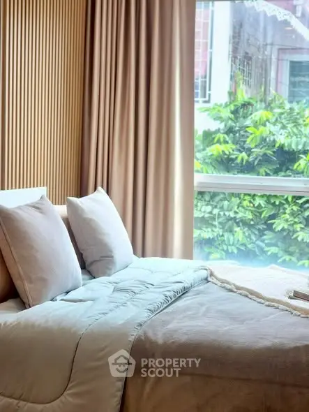 Cozy bedroom with large window and lush greenery view, featuring elegant decor and soft lighting.