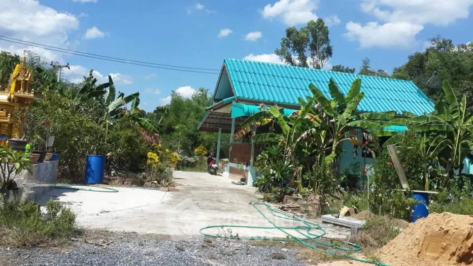Charming rural property with lush garden and vibrant blue roof under clear skies.
