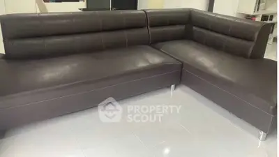 Modern L-shaped brown leather sofa in a sleek living room setting.