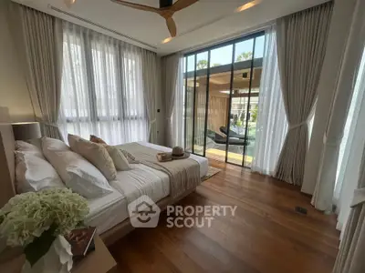 Luxurious bedroom with large windows and balcony, featuring elegant decor and natural light.