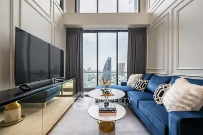 Luxurious living room with stunning city view, elegant decor, and plush blue sofa in high-rise apartment.