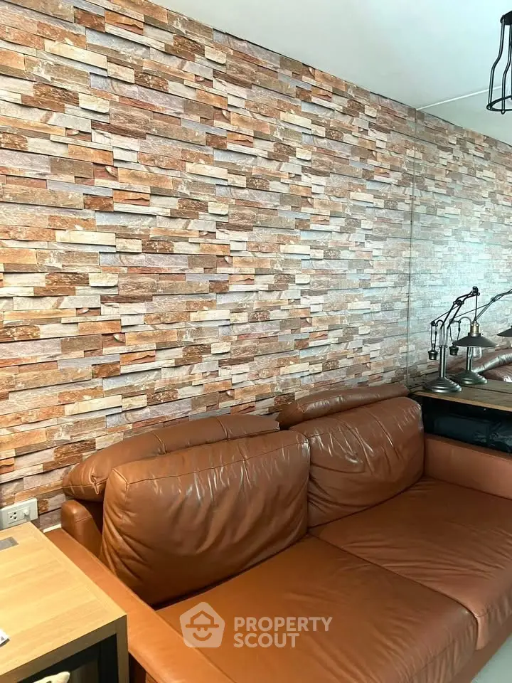 Stylish living room with textured brick wall and leather sofa, perfect for modern urban living.