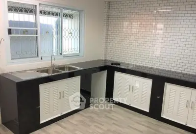 Modern kitchen with sleek black countertops and white cabinetry, featuring a stylish tiled backsplash.
