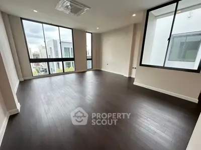 Spacious modern living room with large windows and dark wood flooring