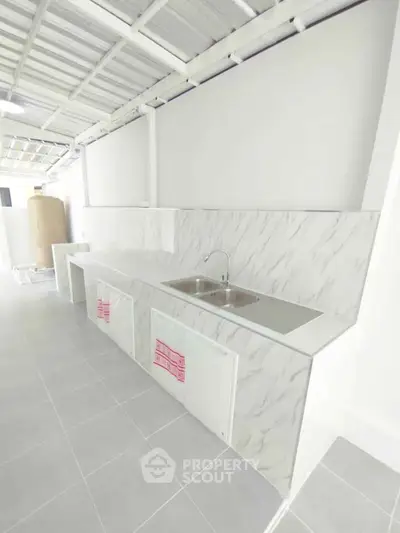 Modern kitchen with sleek marble countertops and dual sink in a bright, open layout.