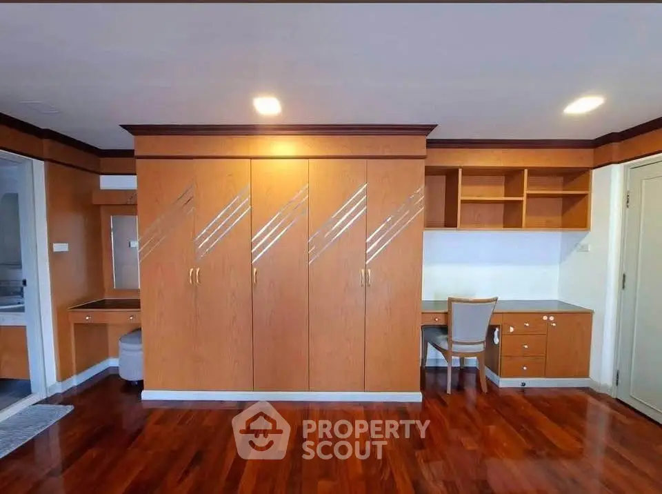 Spacious bedroom with elegant wooden wardrobe and built-in desk, perfect for modern living.