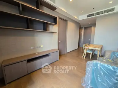 Modern living room with wooden flooring and built-in shelves, featuring elegant furniture and ample natural light.