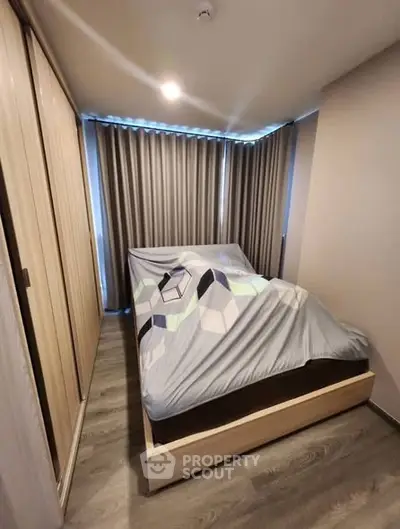 Modern bedroom with stylish geometric bedding and floor-to-ceiling curtains in a cozy apartment.