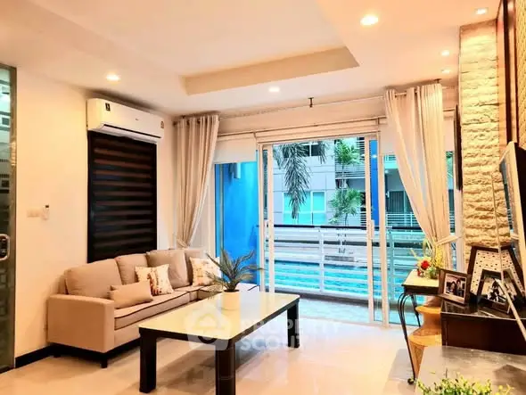 Spacious living room with modern decor and pool view, featuring elegant lighting and comfortable seating.