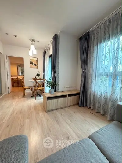 Modern living room with stylish decor and dining area, featuring elegant curtains and wooden flooring.