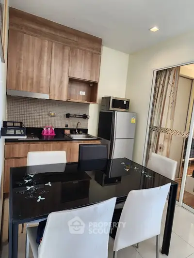 Modern kitchen with sleek black dining table and stainless steel appliances in cozy apartment.