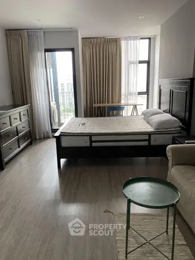 Spacious bedroom with modern furnishings and large windows offering city views.