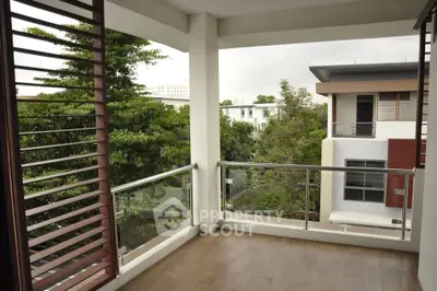 Spacious balcony with modern railing and lush green view in contemporary apartment.