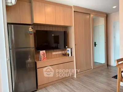 Modern apartment interior with sleek wooden cabinetry and stainless steel fridge.