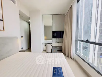 Modern bedroom with large window and city view, featuring sleek furniture and neutral tones.