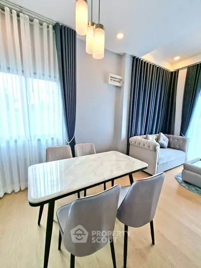 Modern living room with elegant dining area and cozy seating, featuring stylish lighting and floor-to-ceiling curtains.