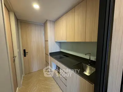 Modern kitchen with sleek cabinetry and black countertop in compact layout.