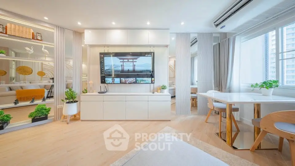 Modern living room with sleek design, large TV, and natural light from windows.