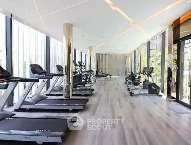 Modern gym with state-of-the-art equipment and floor-to-ceiling windows offering a bright and airy workout space.