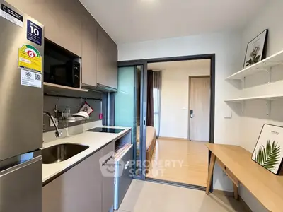 Modern compact kitchen with sleek cabinetry and sliding door leading to cozy bedroom.