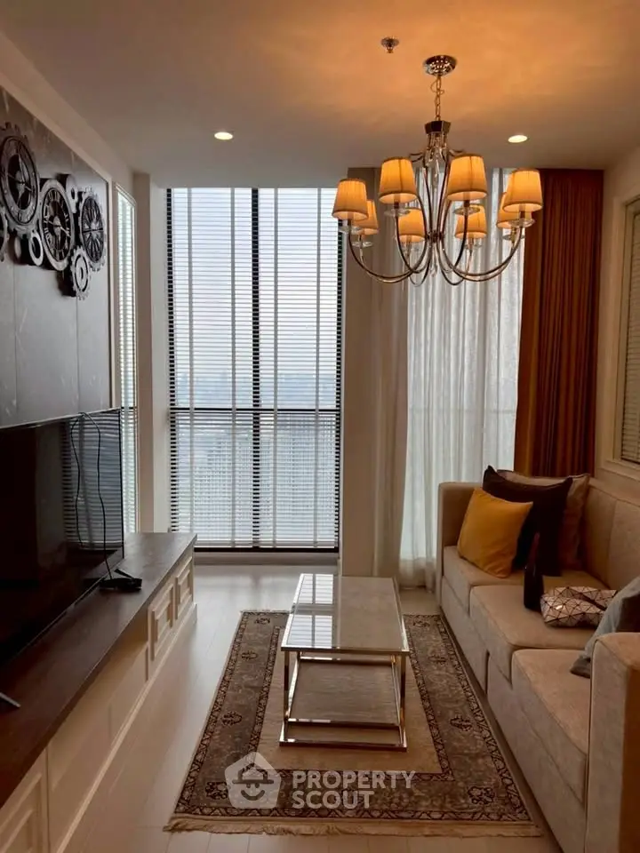 Elegant living room with chandelier and large window offering stunning city view.