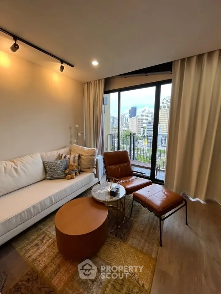 Modern living room with city view, featuring stylish furniture and floor-to-ceiling windows.