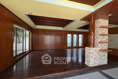 Spacious living room with wooden paneling and large windows, perfect for natural light and modern decor.