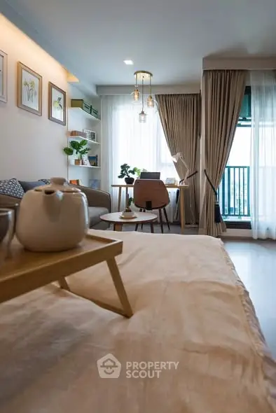 Modern living room with cozy decor and natural light, featuring a stylish seating area and a small balcony.