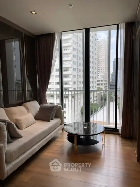 Modern living room with large windows and city view, featuring elegant sofa and coffee table.