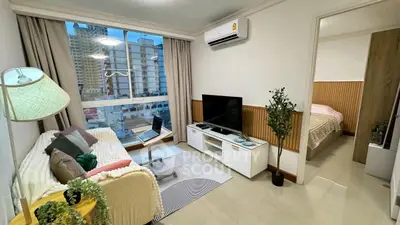 Modern living room with cozy decor and city view, featuring a TV and air conditioning.