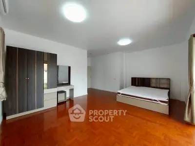 Spacious bedroom with wooden flooring and modern furniture