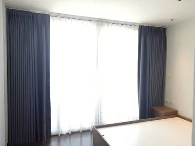 Spacious bedroom with large windows and elegant dark curtains