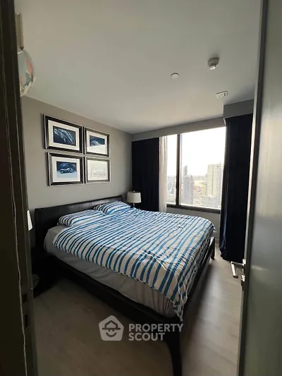Modern bedroom with large window and city view, featuring stylish decor and comfortable bedding.