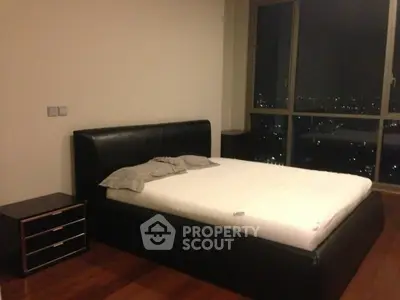 Modern bedroom with city view, featuring sleek black bed and wooden flooring.
