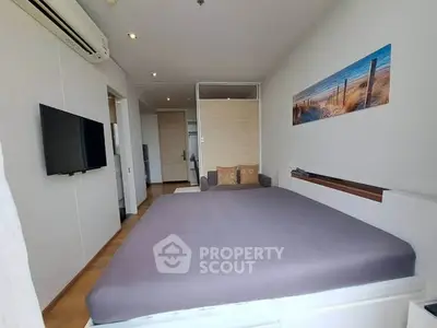 Modern bedroom with minimalist decor and wall-mounted TV in a cozy apartment.