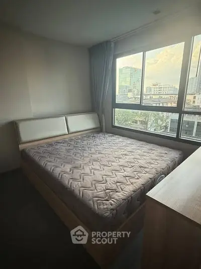 Cozy bedroom with large window offering city view, featuring a comfortable bed and modern decor.
