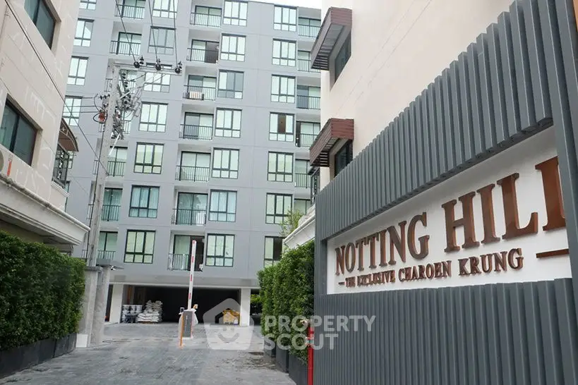 Modern apartment building exterior with Notting Hill sign and gated entrance.