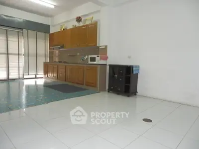 Spacious kitchen with classic wooden cabinetry and ample natural light, featuring modern appliances and glossy tiled flooring.