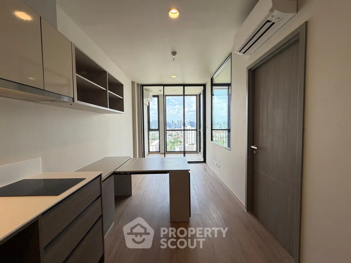 Modern apartment interior with open layout and city view, featuring sleek kitchen and spacious living area.