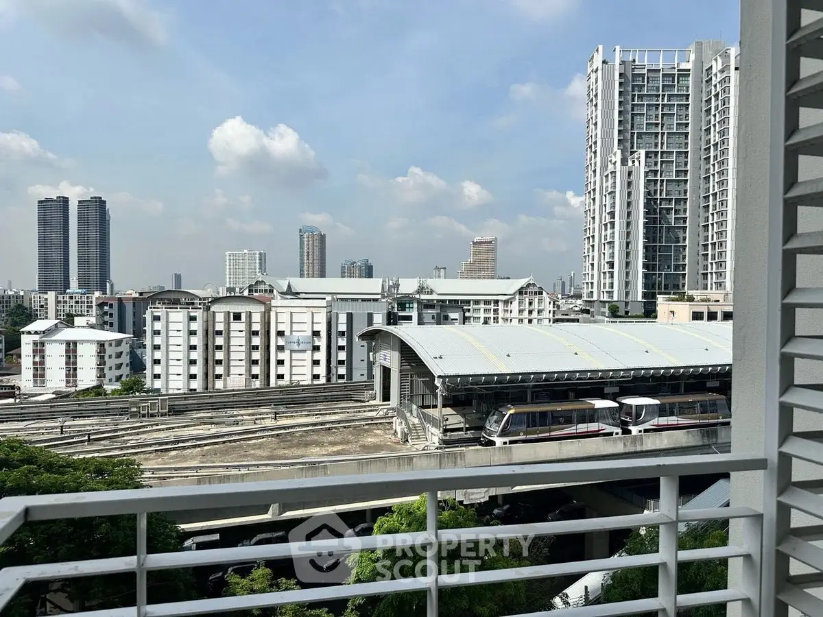 Urban view from balcony overlooking train station and high-rise buildings.