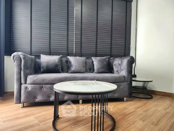 Modern living room with stylish gray sofa and elegant round coffee tables.
