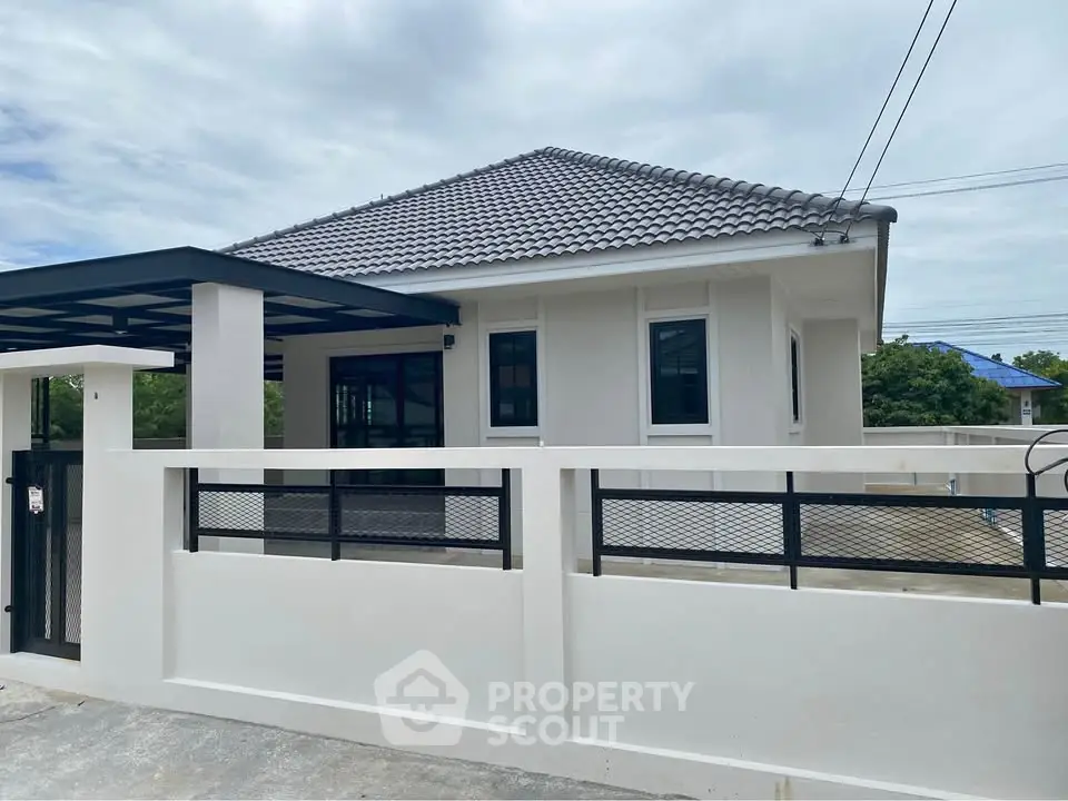 Modern single-story house with tiled roof and gated entrance in a serene neighborhood.