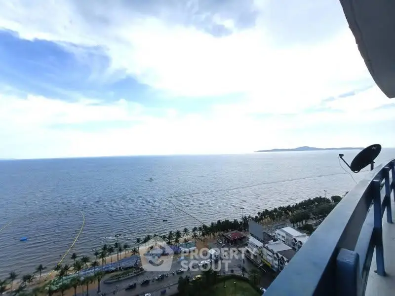 Stunning ocean view from high-rise balcony overlooking beach and palm trees.